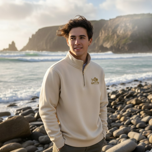 Man wearing an ivory Salty DNA quarter-zip sweatshirt on a beach