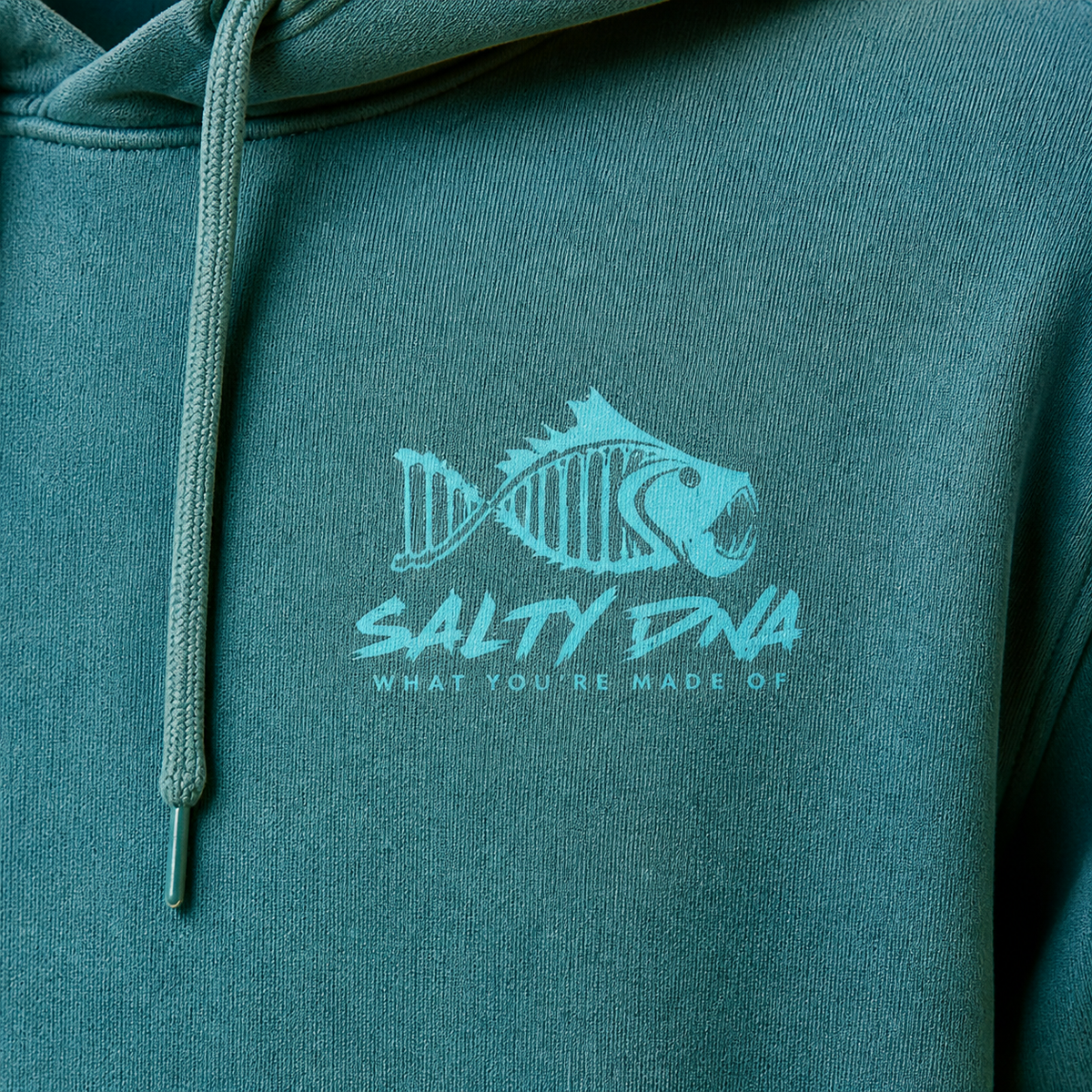 Close-up of the jade Salty DNA Originals Vintage Hoodie chest logo and fabric texture